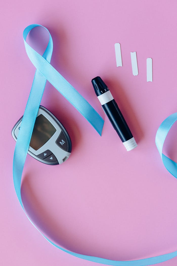 Blue ribbon with glucometer and lancet on pink background, promoting diabetes awareness.